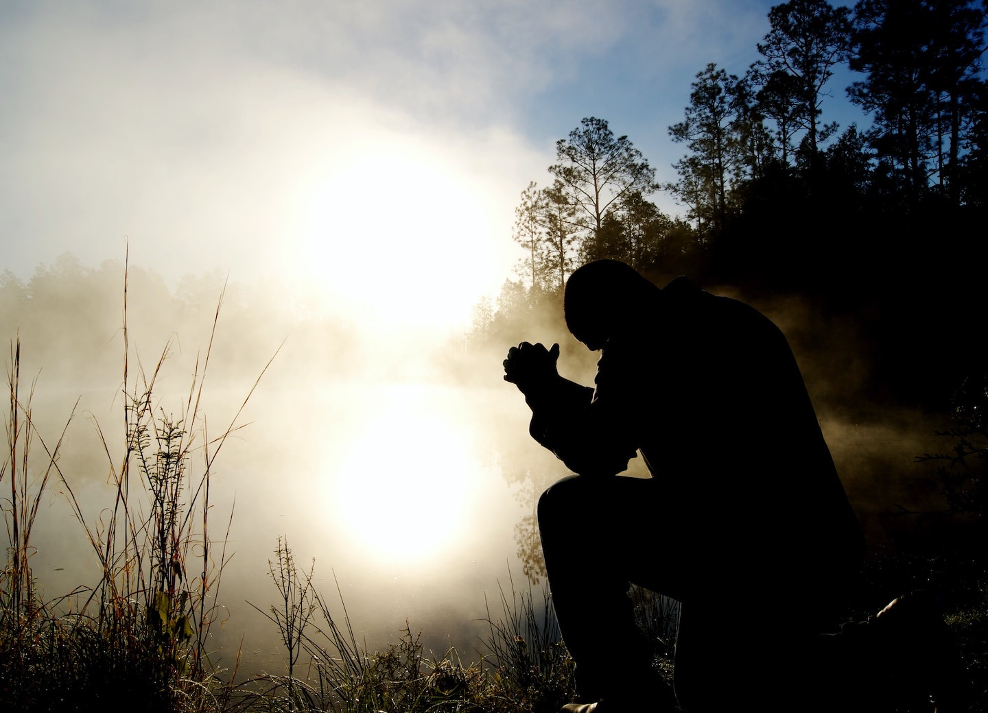 man praying in the morning mist kneeling on ground
